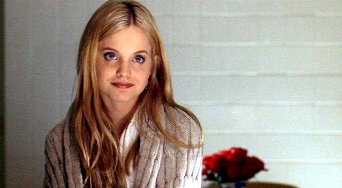 Una adolescente rubia con bata blanca.
