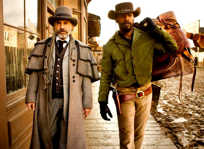 Una escena de la película Django Unchained muestra a dos hombres caminando en un escenario de época.