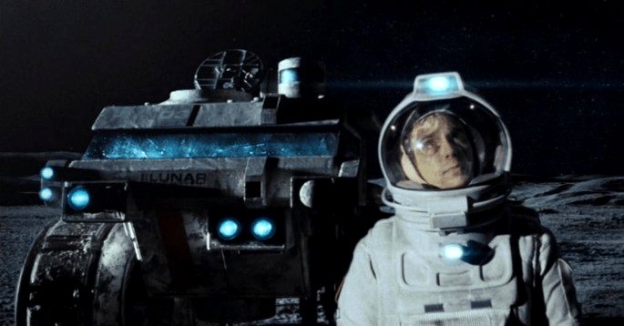 Un astronauta en la luna y un robot detrás de él.