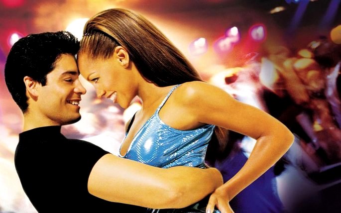 una escena de la película Al ritmo del baile muestra a una pareja sonriendo y mirándose
